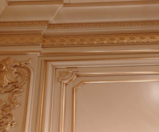 Cornicione e architrave arricchiti con modanature in legno intagliate e finite a foglia oro